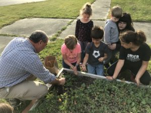 man showing group of children how to plant seeds