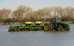 Tractor with plow and fertililzer attachments sitting in flooded field