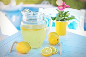 Pitcher of lemonade withlemons around pitcher